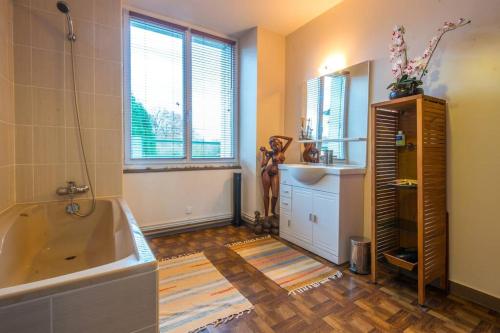 une salle de bain avec une baignoire, un lavabo et un miroir dans l'établissement Ti Laouen, Maison traditionnelle Bretonne, à Les Brulais