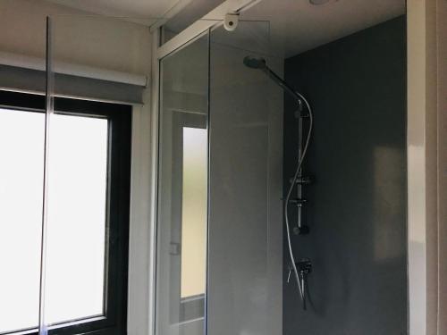 une salle de bain avec une douche avec une porte vitrée dans l'établissement Camping La Vaugelette - Drôme, à Montclar Sur Gervanne