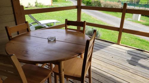 a wooden table and chairs on a porch with a window at La Grange du Héron in Balaguier-dʼOlt