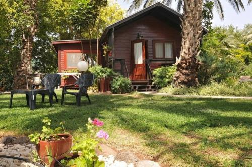 a cabin with a table and chairs in a yard at בקתה בתמרים in Moshav Ramot