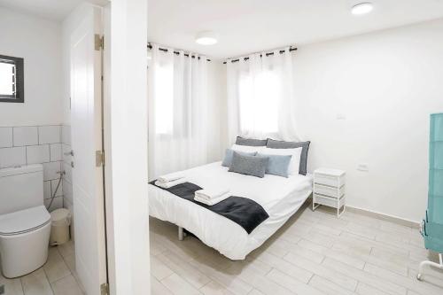 a white bedroom with a bed and a toilet at YalaRent Cliff side villa with private pool in Eilat