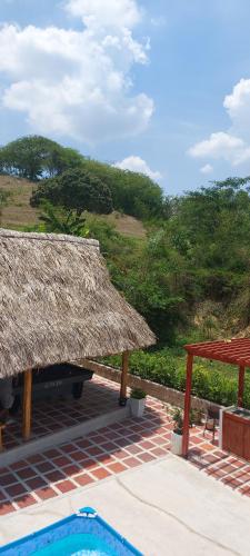 a resort with a straw roof and a swimming pool at La Casa de Tita _ Usiacuri in Usiacurí