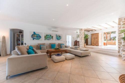 una gran sala de estar con sofás y una mesa. en Villa en San José con vistas al mar, piscina y 7 habitaciones, en Cala Vadella