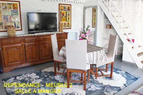 a dining room with a tv and a table and chairs at Chez Martine et Bernard in Saint-Vincent-Sterlanges