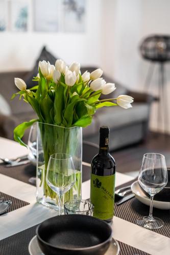 a table with a bottle of wine and a vase of flowers at Appartamenti Vasco Renna Surf Center in Nago-Torbole