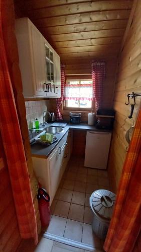 uma pequena cozinha num chalé de madeira com um lavatório em Ferienhaus Hensel em Großzerlang