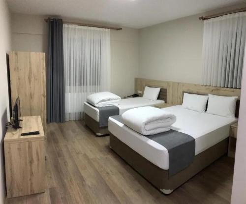 a bedroom with two beds and a television in it at Şavşat Köşk Otel in Artvin