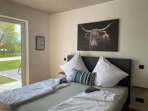 1 dormitorio con 1 cama con una foto de toro en la pared en Neubau Grüner Wolpertinger Designwhg 106qm Barrierefrei en Breitbrunn am Chiemsee