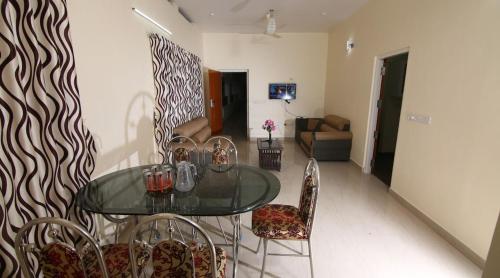 a dining room with a glass table and chairs at Thanungattil Towers in Changanācheri