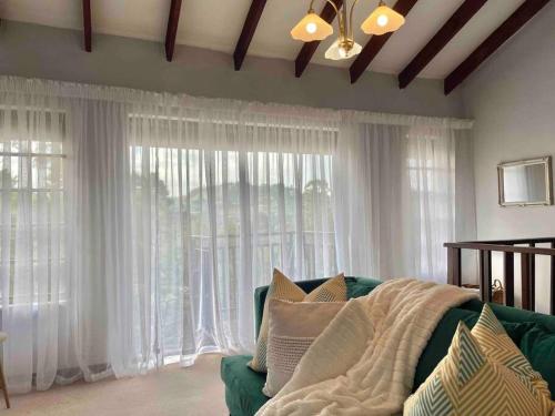 ein Wohnzimmer mit einem grünen Sofa und einem großen Fenster in der Unterkunft Separate entry cozy Guesthouse in Hillcrest