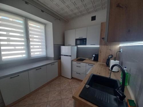 una cocina con armarios blancos y fregadero en Apartament Ogrodzieniec en Ogrodzieniec