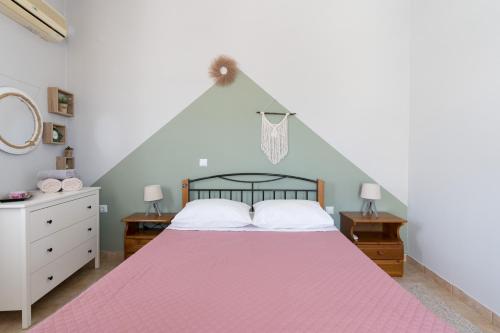 a bedroom with a bed with a pink bedspread at The City Apartment in Lixouri