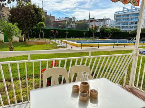 uma mesa branca e cadeiras numa varanda com piscina em Domuum Holidays - DMS III POOL em Salou