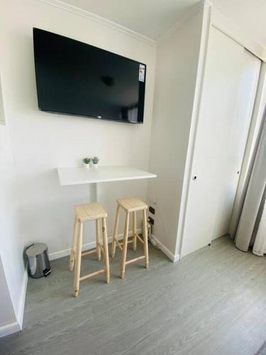 a room with two stools and a table with a tv on the wall at Vista Cordillera Studio in Santiago