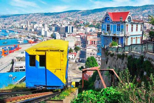a yellow and blue train car on the tracks near a city at Vista Cordillera Studio in Santiago