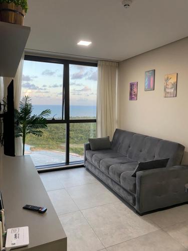 a living room with a couch and a large window at Apartamento no 20º andar Barra Home Stay in Recife