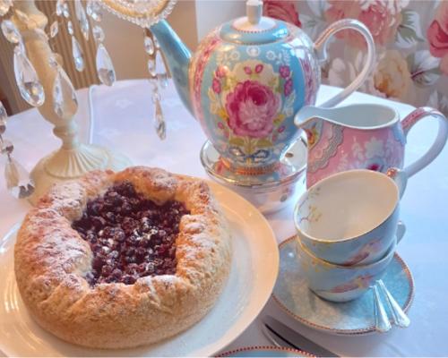 a pie on a plate with a cup and a tea pot at Linden Lodge Stays in Saint-Claud