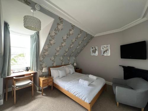 a bedroom with a bed and a chair and a television at Gladstone House in Edinburgh