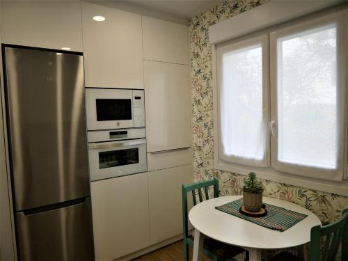 a kitchen with a table and a stainless steel refrigerator at El Manzanal - gateway to the mountains and Bilbao in Llodio