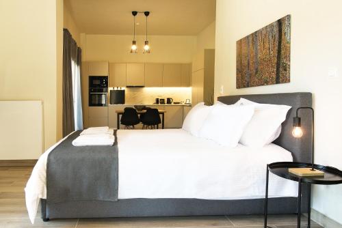 a bedroom with a large white bed and a kitchen at Aellō luxury apartments in Markopoulo