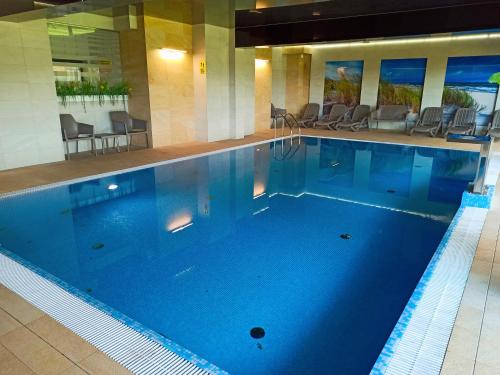 a large blue swimming pool in a hotel at Lulu Apartments - Apartament FRIDA blisko morza - Resort Kołobrzeg parking i basen z sauną w cenie in Kołobrzeg