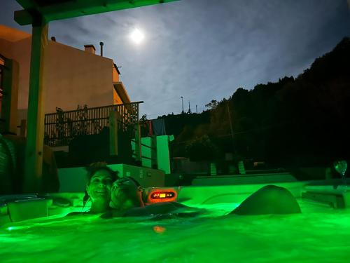 a couple of people in a swimming pool at night at B&C Furnas House in Furnas