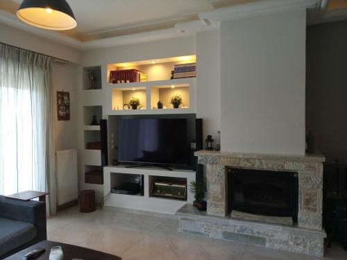 a living room with a fireplace and a flat screen tv at Villa Tsios in Artemida