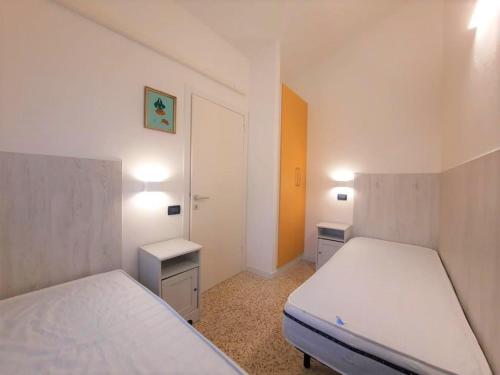 una piccola camera con due letti e due tavoli di Villa Wanda 2 a Bibione