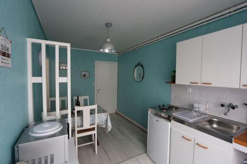 una cucina con pareti blu, armadi bianchi e lavandino di Appartement de vacances proche du Mont Saint Michel a Roz-sur-Couesnon