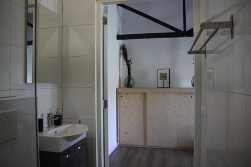 Baño blanco con lavabo y espejo en B&B Hoeve de Veldmaat, en Haaksbergen