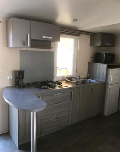 une cuisine avec une cuisinière et un comptoir dans l'établissement Mobile Home tout confort climatisé 4 à 6 personnes Camping Les Salins de la Gardiole ancien camping de L'Europe à Vic La Gardiole, à Vic-la-Gardiole