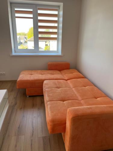 a bedroom with a large orange couch and a window at Centro apartamentai in Kalvarija