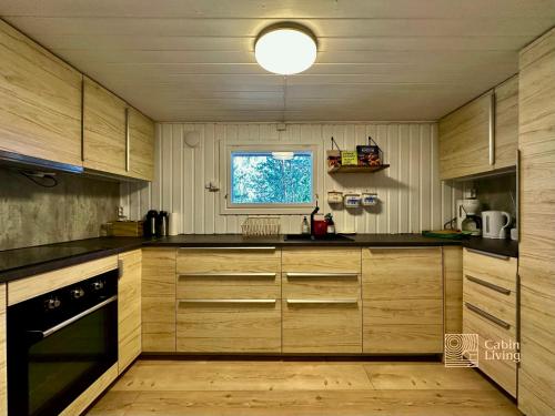 een keuken met houten kasten en een raam bij Summer Cabin Nesodden sauna, ice bath tub, outdoor bar, gap hut in Brevik