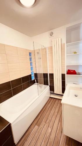 La salle de bains est pourvue d'une baignoire blanche et de carrelage noir et blanc. dans l'établissement L'Ecureuil, à Gérardmer