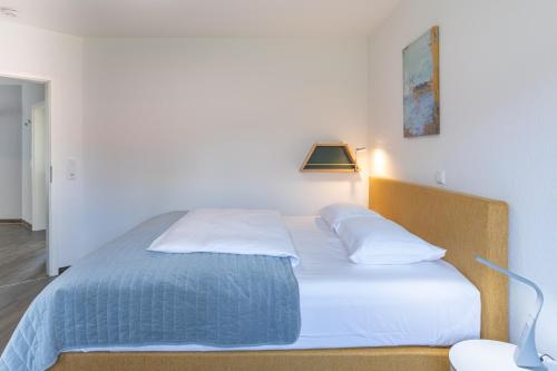a bed with white sheets and pillows in a room at Windrose in Drelsdorf