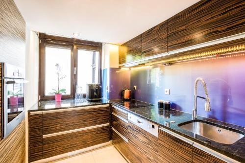 een keuken met houten kasten, een wastafel en een raam bij Apartment Sare 11 in Krakau