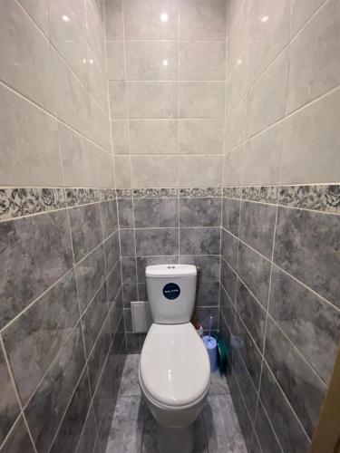 baño con aseo y pared de azulejos en DEYA en Petropavlovsk