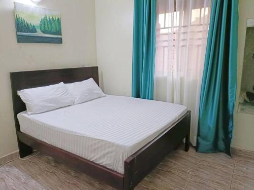 a bed sitting in a room with a window at Amaryllis homes , within city centre,near River Nile in Jinja