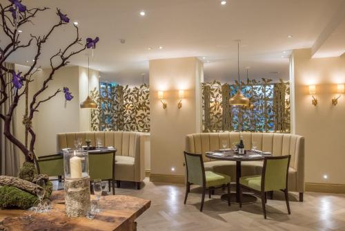 a restaurant with tables and chairs and paintings on the walls at Careys Manor Hotel & SenSpa in Brockenhurst