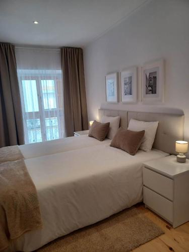 a large white bed in a bedroom with a window at Flor da Laranjeira in Elvas