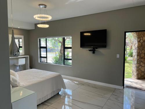 a bedroom with a bed and a flat screen tv at Swan Lake Suites in Benoni
