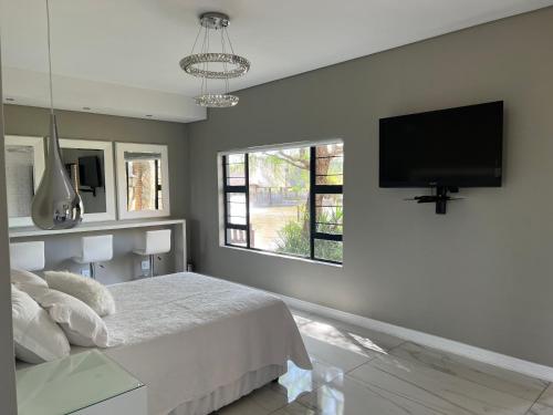 1 dormitorio con 1 cama y TV de pantalla plana en Swan Lake Suites en Benoni