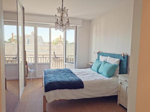 - une chambre avec un lit doté d'oreillers bleus et d'un lustre dans l'établissement Grand Appartement Familial, Tours Centre, Parking, à Tours