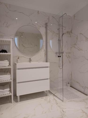 a white bathroom with a sink and a shower at Flor da Laranjeira in Elvas