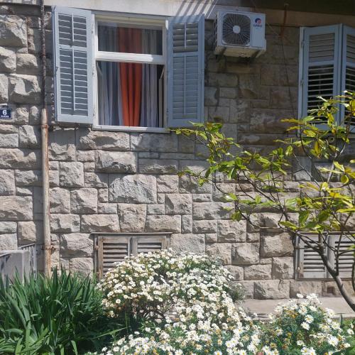 a stone building with blue windows and flowers at Central Jardin Guest House Split in Split