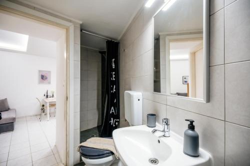 a bathroom with a sink and a toilet and a mirror at Joseph Seaside Apartment in Heraklio