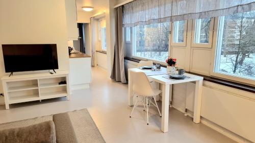 a living room with a white table and a tv at Aparthotel Clock 19 in Kotka