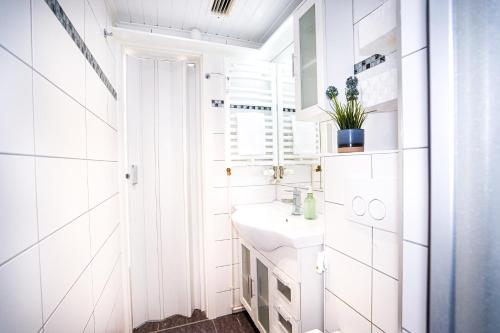 a white bathroom with a sink and a window at Wiet Kieker - mit bestem Meerblick in Sierksdorf