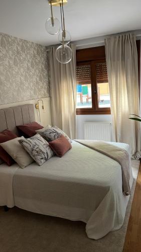 1 dormitorio con 1 cama blanca grande con almohadas en El Retiro de Villaviciosa, en Villaviciosa