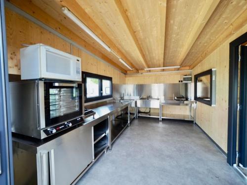 a large room with a kitchen with a tv at Holzhütte J23 klein in Reichenau